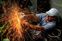 a-worker-uses-a-grinder-with-sparks-flying-off-it-AXWGJ7.jpg